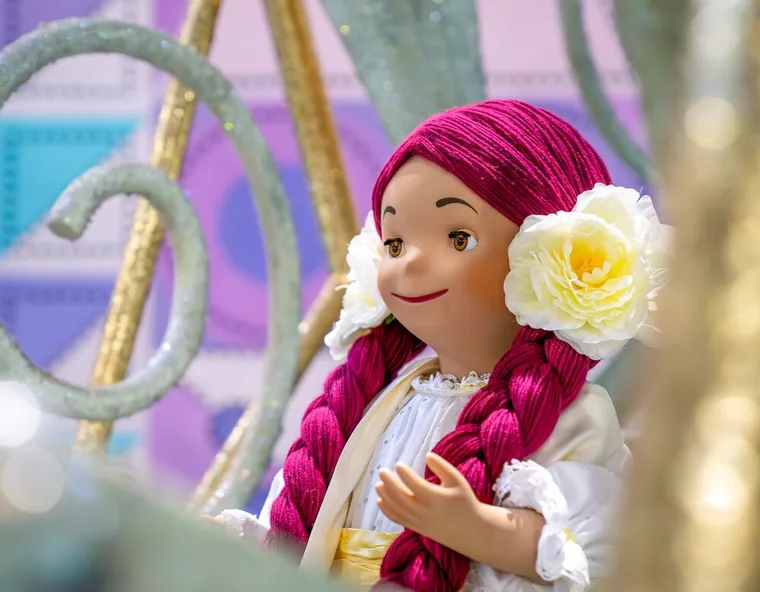 Its a Small World doll with vibrant purple hair, and flowers